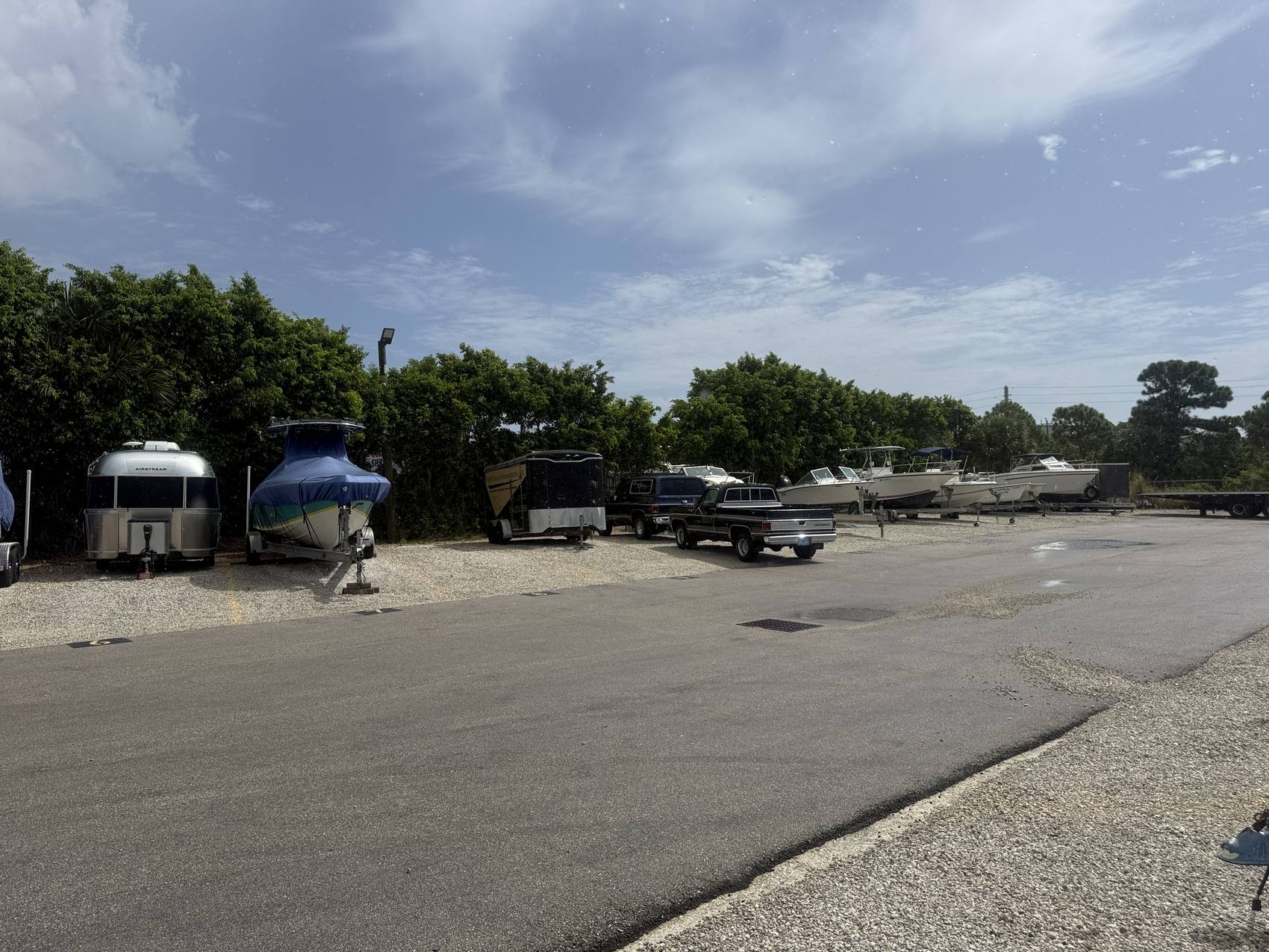 Boats on trailers, an Airstream, cargo trailers and pickup trucks parked in rows at the Hypoluxo Dry Dock storage yard.
